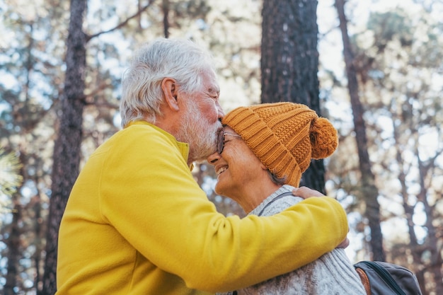 Head shot portrait close up of old people smiling and enjoying looking each other in the forest of mountain Cute couple of mature seniors in love feeling happy and taking care