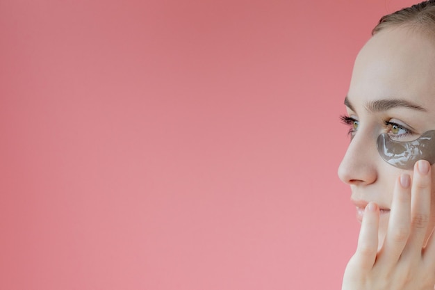 Head shot portrait close up smiling young woman with under eye moisturizing patches mask looking at camera enjoying skincare procedure