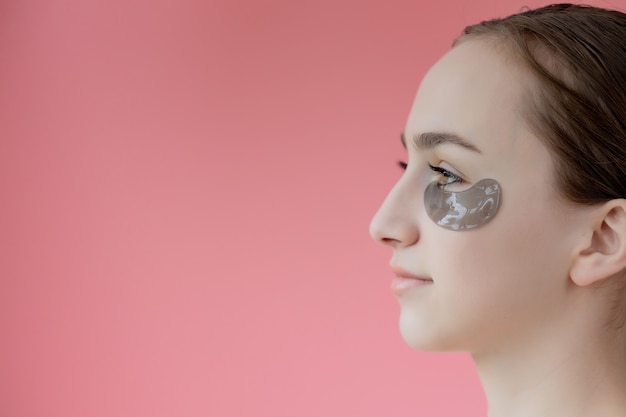 Head shot portrait close up smiling young woman with under eye moisturizing patches mask looking