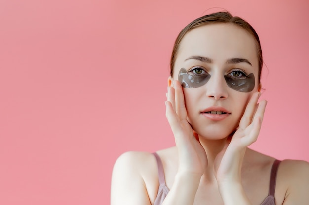 Head shot portrait close up smiling young woman with under eye moisturizing patches mask looking 