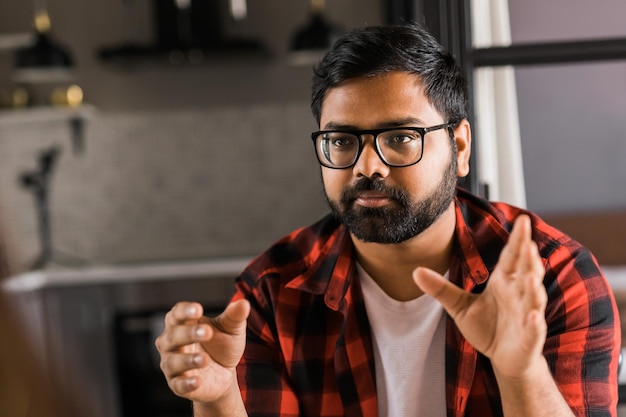 Head shot portrait smart confident smiling millennial indian man Handsome hindu student guy freelancer at home