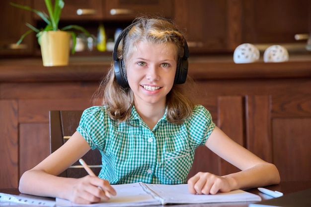 Head shot of a preteen girl wearing headphones looking at the webcam at home