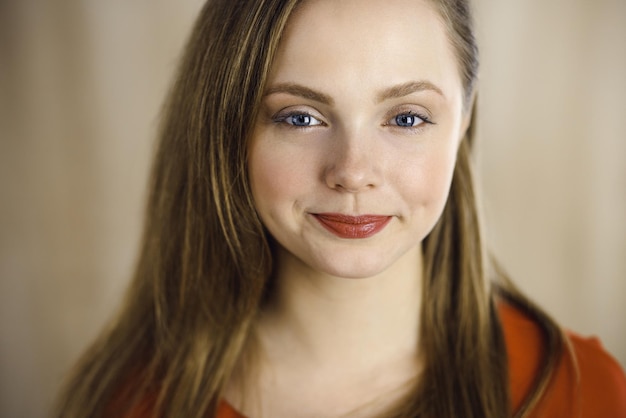 Head shot of a smart confident smiling millennial european woman standing with folded arms at home Attractive young teenager student girl freelancer looking at camera dressed in red