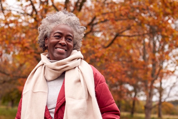 Photo head and shoulders portrait of senior woman on walk through autumn countryside against golden leaves