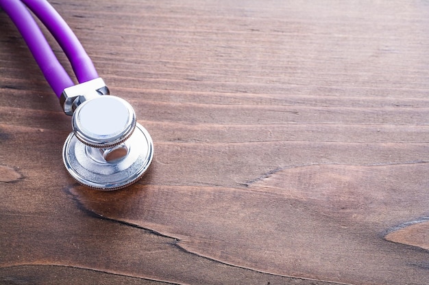 Head of stethoscope on vintage wooden board with organized copyspace medical concept