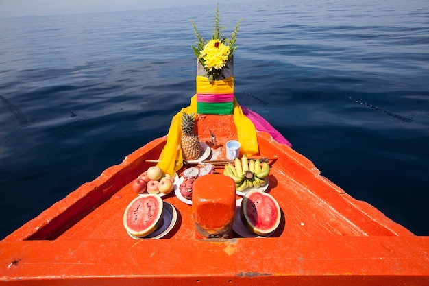 Photo head of thai local fisherman boats, decorated with long fabric strips in various color and fruits respect to the faith