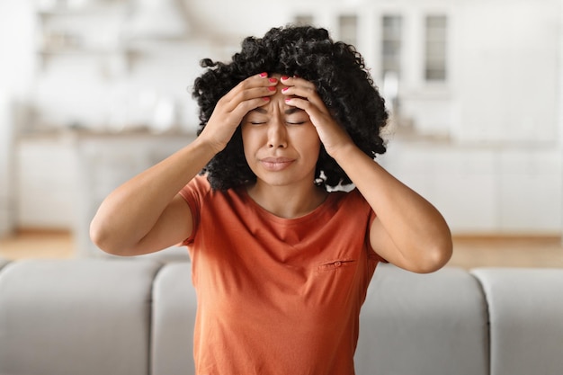 Фото Концепция головной боли молодая чернокожая женщина страдает от мигрени дома