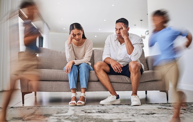 Photo headache kids running and parents on a sofa in a living room suffering stress anxiety and adhd children family autism and burnout crisis with woman and man in mental health and energy problem