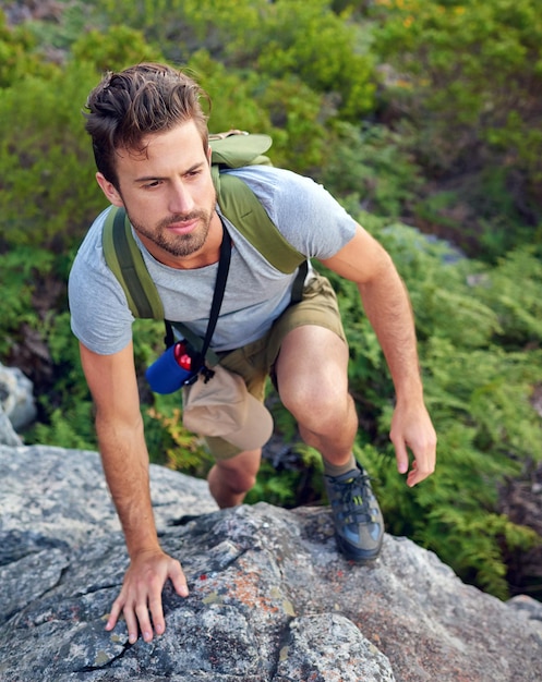 正しい方向に向かって山をスケーリングするハンサムな若い男のショット