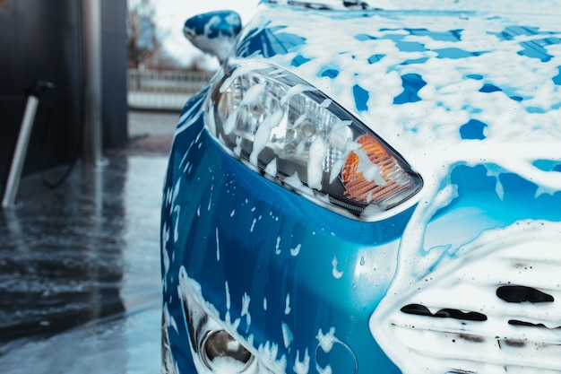 Headlight of a blue man in foam from car shampoo