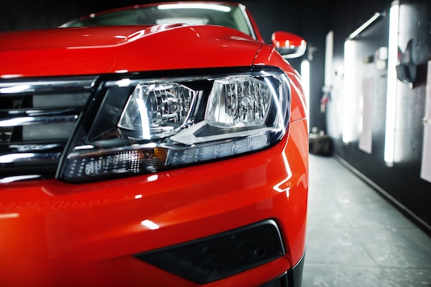 Headlight of nice and new orange sport suv car in modern garage.