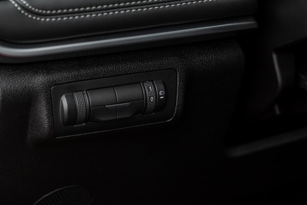 Headlights corrector adjustment buttons. ÃÂÃÂ¡lose up view of the modern car black interior.