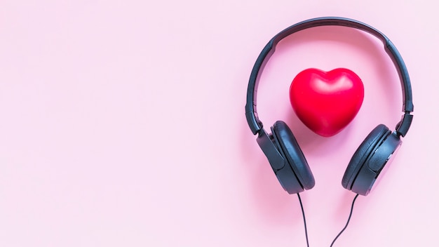 Photo headphone around the red heart shape against pink backdrop