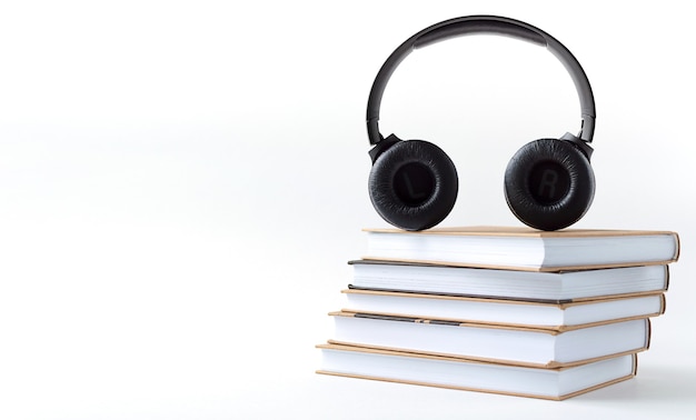 Headphones and books on a white background. Audiobook concept with copy space.