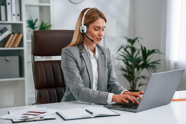 in headphones by laptop call center woman in business formal clothes is working in office