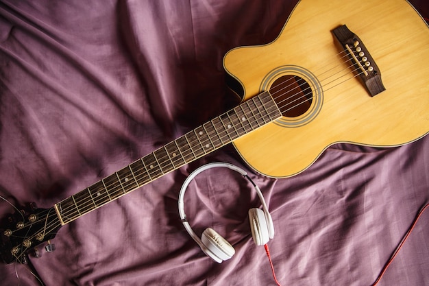 Cuffie e chitarra classica a letto