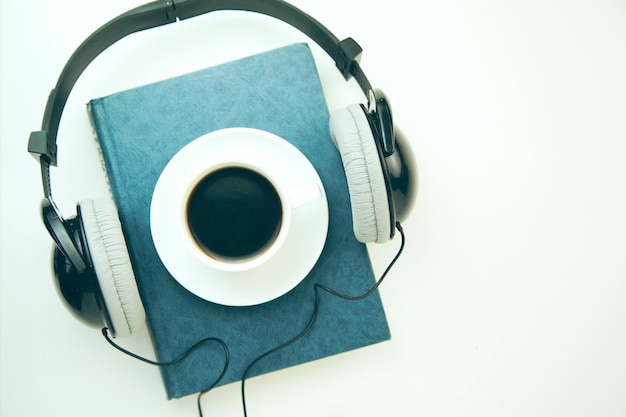 Headphones, coffee and book on white  table