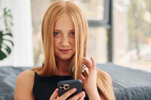 In headphones Female teenager with blonde hair is at home at daytime