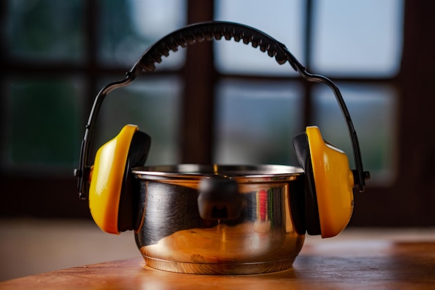 Headphones from sound on kitchen pot on wooden table