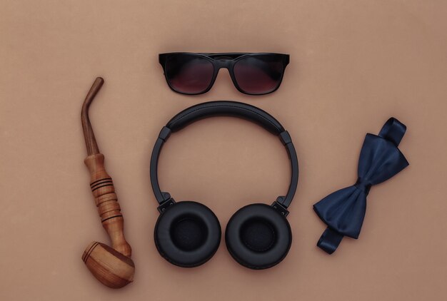 Headphones and gentleman's accessories on brown background. Top view