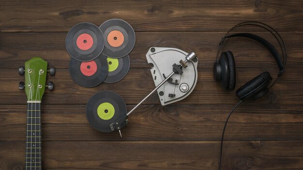 Headphones guitar and player with vinyl discs on a wooden background Retro technique for playing music