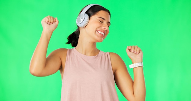 Headphones happy woman and dancing to music on green screen studio and backdrop dance female model and listening to audio album streaming media and sound of radio subscription podcast or energy