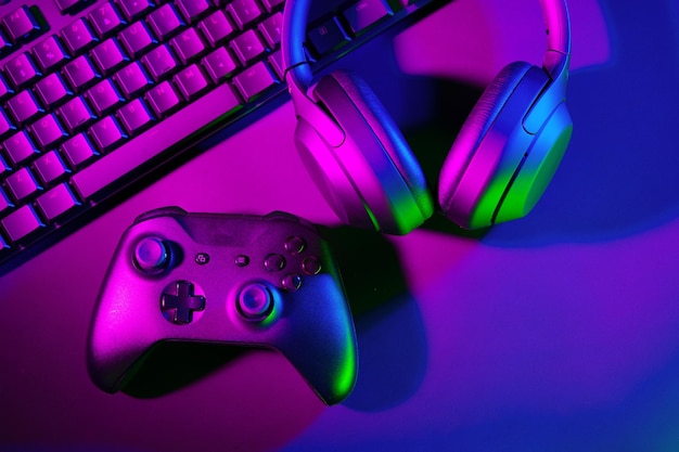 Headphones joystick and computer keyboard on black table