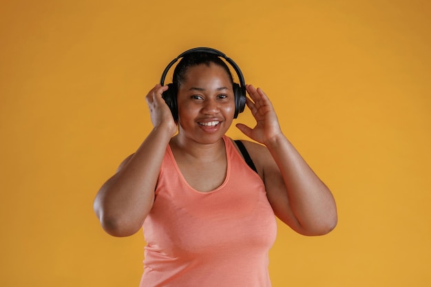 Foto con le cuffie che ascoltano musica una donna afroamericana è in studio contro uno sfondo giallo