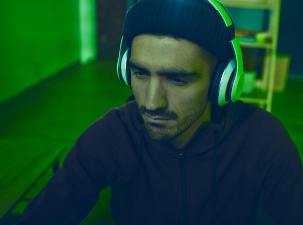 headphones man or hacker programming or coding for cybersecurity online crime or cyber attack neon big data or programmer reading software info for hacking or streaming radio on dark web at night