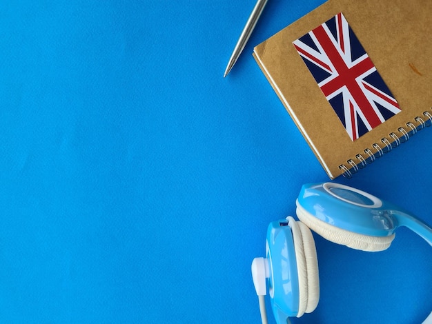 Headphones and notebook with the flag of britain on blue background