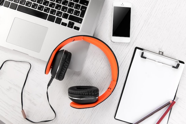 Headphones and other devices on wooden desktop closeup