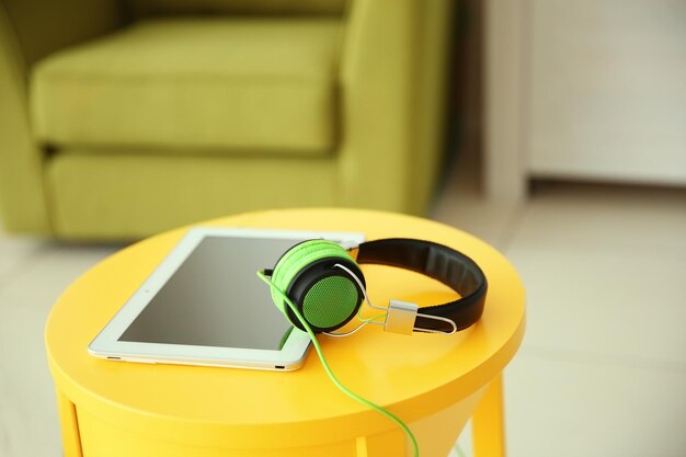 Photo headphones and tablet on the table on furniture background