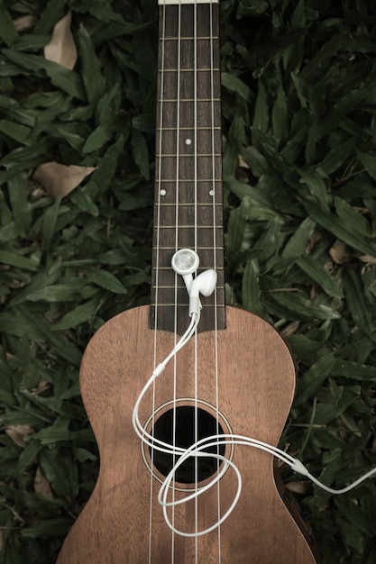 Foto cuffie e ukulele sull'erba. concetto di musicoterapia