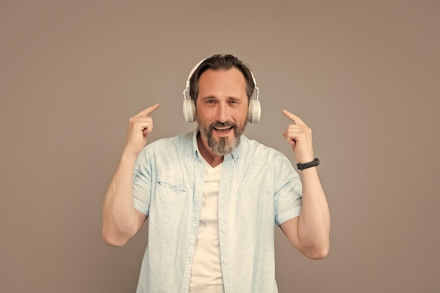 ヘッドフォンの音量を上げる 幸せな老人がヘッドフォンを指さす 音楽を聴く レジャー 歌を聴いて世界を忘れる