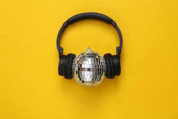 노란색 배경 미니멀리즘 파티 개념에 디스코 볼이 있는 헤드폰