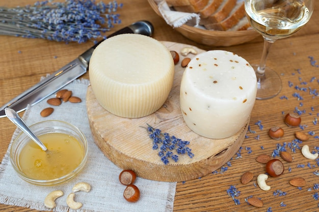 Heads of fresh organic artisan cheese with honey nuts and lavender on a wooden background