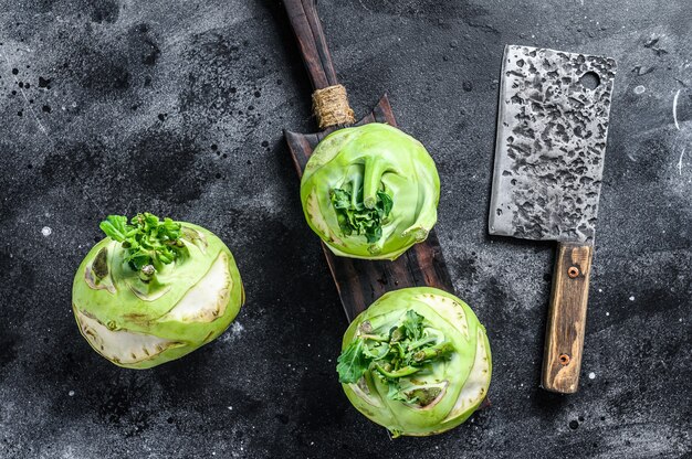 Heads of fresh ripe white cabbage kohlrabi. Black background. Top view.