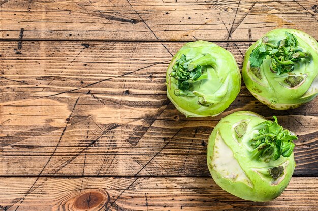 Heads of fresh ripe white cabbage kohlrabi. Wooden background. Top view.