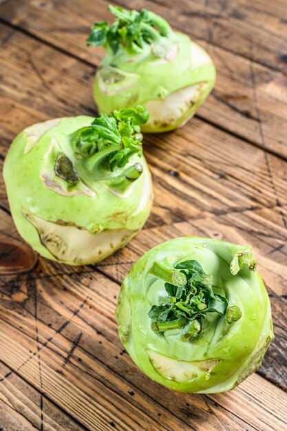 Photo heads of fresh ripe white cabbage kohlrabi. wooden background. top view.