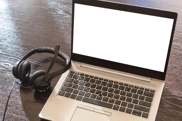 Photo headset on a laptop blank white screen wooden table background