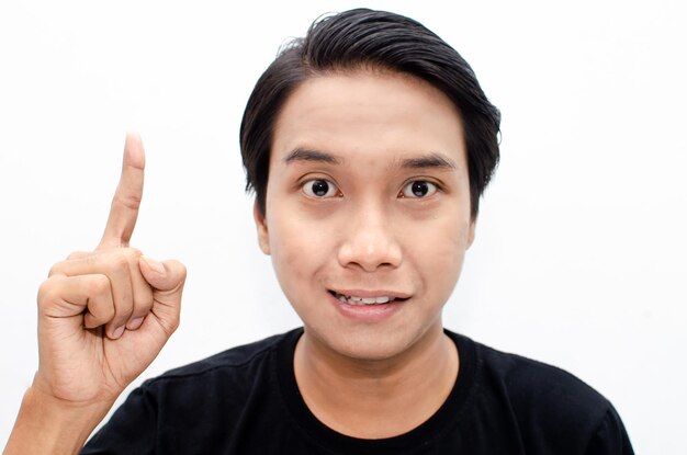 headshot of asian young man shocked happily pointing up to copy space