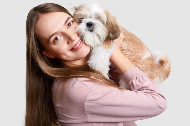 Headshot of attractive female holds pedigree dog near face