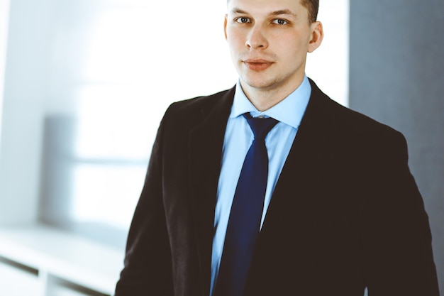 Headshot of businessman standing straight in office. Success and business workplace concept