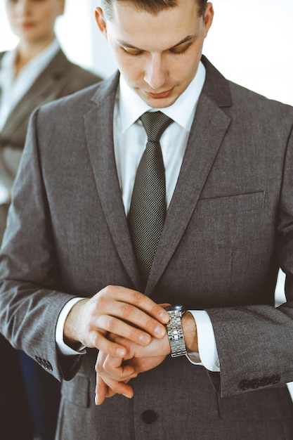 Headshot of businessman standing straight with colleagues at background in office. Group of business people discussing questions at conference or presentation. Success and business concept.