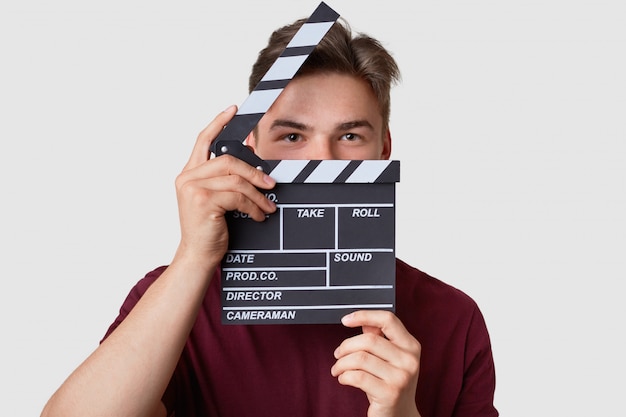 Photo headshot of handsome man hides face with clapper board