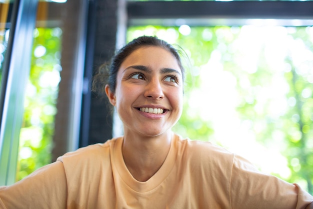 Headshot of indian woman sit on potdoor cafe waving hand looks\
to camera make video call chat use computer laptop webcam view\
vlogger record webinar job interview distantly concept