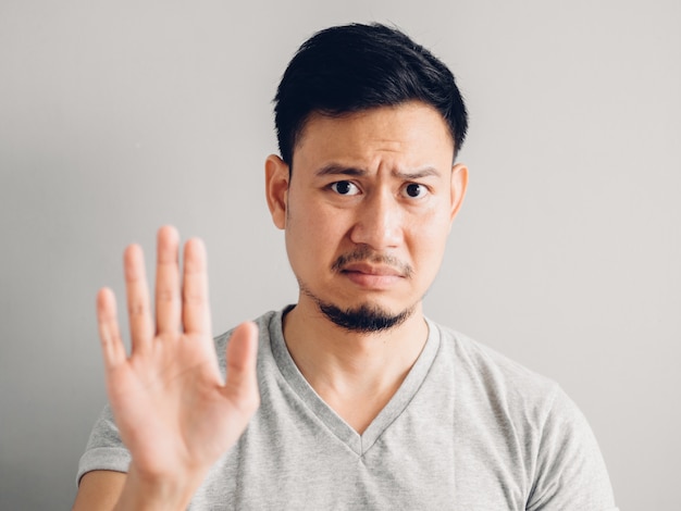 Headshot photo of Asian man with hate and disgusting face on grey background.