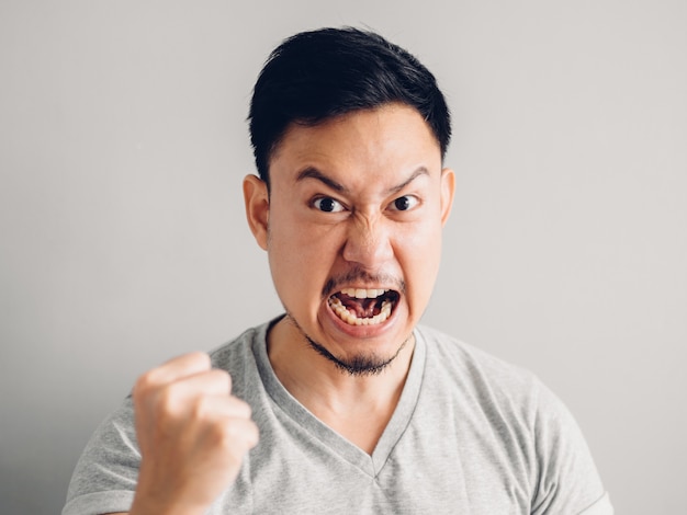 사진 분노와 분노 얼굴을 가진 아시아 남자의 얼굴 만 사진. 회색 배경에.