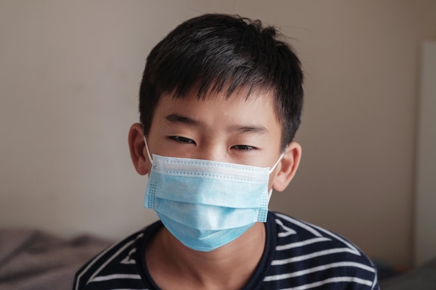 Headshot portrait of sicked preteen teenager Asian boy wearing a mask