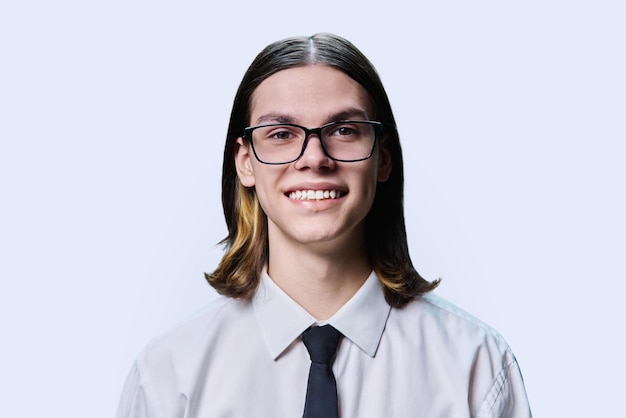 Headshot portrait of smiling teenage guy on light studio background